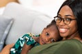 Happy young African American mother having fun with daughter child girl playing and hugging in bedroom at home Royalty Free Stock Photo