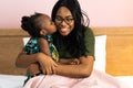 Happy young African American mother having fun with daughter child girl playing and hugging in bedroom at home Royalty Free Stock Photo