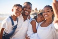 Happy young african american mother holding camera while taking a selfie at the beach with her husband and two children Royalty Free Stock Photo