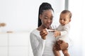 Happy young African American mother looking at thermometer