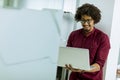 Happy young African American IT specialist wearing glasses working on his laptop in the office Royalty Free Stock Photo