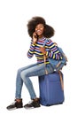 Happy young african american travel woman sitting on suitcase and talking on mobile phone Royalty Free Stock Photo