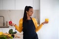 Happy young african american woman in apron hold red and yellow pepper in hands at table with organic vegetables Royalty Free Stock Photo