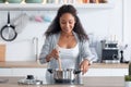 Happy young african american woman cooking healthy food in casserole in the kitchen at home