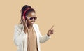 Happy young african american woman in headphones listens to music on beige background. Royalty Free Stock Photo