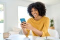 Happy young African American woman at home using mobile cell phone. Royalty Free Stock Photo