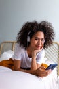 Happy young African American woman listening to music with headphones app mobile phone app looking at camera. Royalty Free Stock Photo