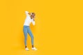 Happy young African American woman listening  to music on headphones  on yellow studio background with copy space Royalty Free Stock Photo