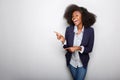 Happy young african american woman pointing fingers against gray background