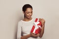 Happy young African American woman with red gift present box in her hands on white background Royalty Free Stock Photo