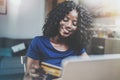 Happy young african american woman shopping online through laptop using credit card at home. Horizontal,blurred Royalty Free Stock Photo