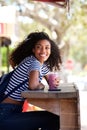 Happy young african american woman sitting outdoors holding smoothy drink