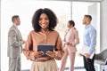 Happy young African business woman holding tablet standing in office. Portrait. Royalty Free Stock Photo