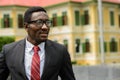 Happy young African businessman with eyeglasses thinking in the city streets outdoors Royalty Free Stock Photo