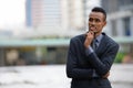 Happy young African businessman thinking in the city streets outdoors Royalty Free Stock Photo