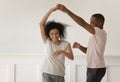 Happy young african couple holding hands dancing laughing at home