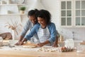 Happy young African couple wearing aprons cooking homemade bakery foods