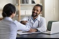 Happy young african doctor shaking hands with indian patient. Royalty Free Stock Photo