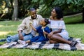 Happy young African family playing with soap bubbles with their cute little daughter in park outdoors in summer or Royalty Free Stock Photo