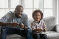 Happy young african father involved in video game with son.