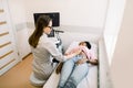 Happy young African female patient going through abdomen ultrasound at clinic. Professional Caucasian woman doctor doing