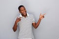 Happy young african man pointing away against gray background Royalty Free Stock Photo