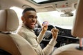 Happy young african man showing his driver& x27;s license while driving a car Royalty Free Stock Photo