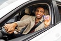 Happy young african man showing his driver& x27;s license from open car window Royalty Free Stock Photo