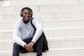 Happy young african man sitting on steps and listening to music with headphones Royalty Free Stock Photo