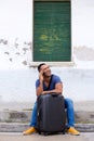 Happy young african man sitting with suitcase and talking on mobile phone Royalty Free Stock Photo