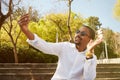 Happy young African man in white shirt and talking on the mobile phone and gesturing while sitting outdoors Royalty Free Stock Photo