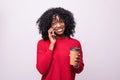 Happy young african woman casually dressed talking on mobile phone, holding takeaway cup of coffee standing isolated over gray Royalty Free Stock Photo
