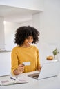 Happy young African woman customer holding credit card using laptop in kitchen. Royalty Free Stock Photo