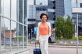 Happy young african woman with travel bag in city