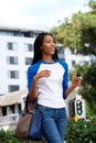 Happy young african woman walking with bag and mobile phone Royalty Free Stock Photo