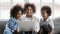 Happy young african woman watching movie on computer with kids. Royalty Free Stock Photo