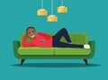Happy young afro american man with TV remote control lying on sofa isolated.