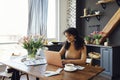 Happy young afro american woman sitting at home using laptop and typing on keyboard. Smiling female student or freelancer looking Royalty Free Stock Photo