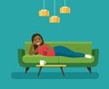 Happy young afro american woman with TV remote control lying on sofa isolated.