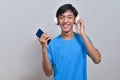 Happy young Asian boy teenager holding a mobile phone, listening to music with his headphones Royalty Free Stock Photo