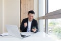 Happy young Asian business man in office looking at mobile phone, with emotion winner or win, financial stock sports betting. Royalty Free Stock Photo