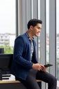 Young asian business man work and holding smartphone in modern office on computer Royalty Free Stock Photo