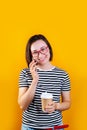 Happy young asian business woman talking by mobile phone drinking coffee on yellow background Royalty Free Stock Photo