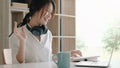 Happy young asian business woman waving hands to greeting partner during making video conference with her team Royalty Free Stock Photo