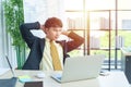 Happy young asian businessman in formal dress sitting on chair with relax in modern office with computer laptop on table in workpl Royalty Free Stock Photo