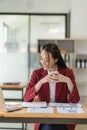 Happy young asian businesswoman celebrating success with arms raised in front of laptop with excitement at office Royalty Free Stock Photo