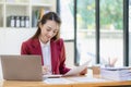 Happy young asian businesswoman celebrating success with arms raised in front of laptop with excitement at office Royalty Free Stock Photo