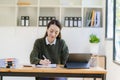 Happy young asian businesswoman celebrating success with arms raised in front of laptop with excitement at office Royalty Free Stock Photo