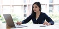 Happy young asian businesswoman sitting on her workplace in the office. Young woman working at laptop in the office. Royalty Free Stock Photo