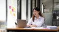 Happy young asian businesswoman sitting on her workplace in the office. Young woman working at laptop in the office. Royalty Free Stock Photo